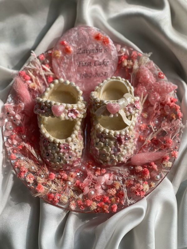 Baby’s fondant shoes from first birthday cake preserved in flowers and resin , Mustcrafts